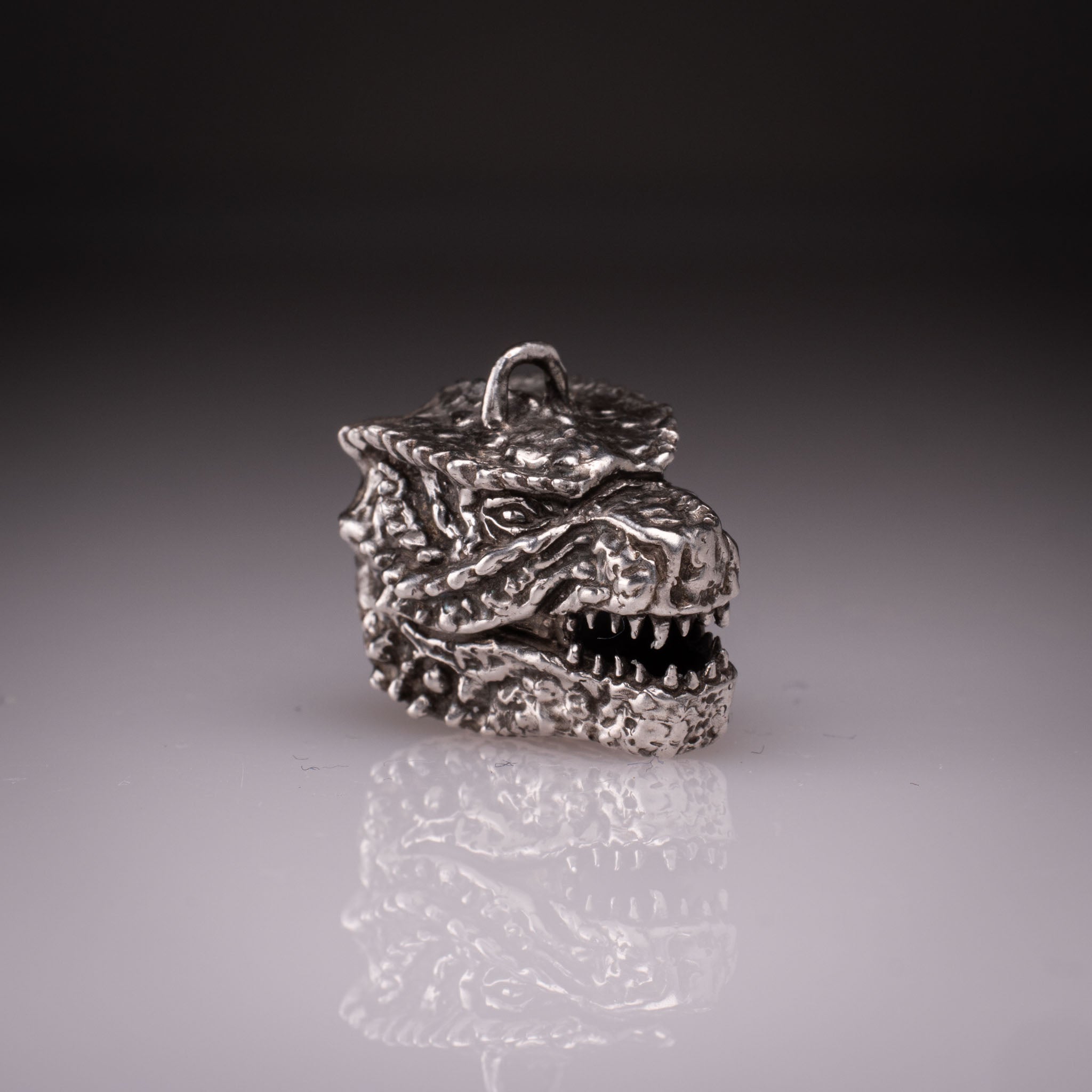 925 Sterling Silver Godzilla head pendant featuring detailed scales, sharp teeth, and oxidized finish, handcrafted by KaijuLab.
