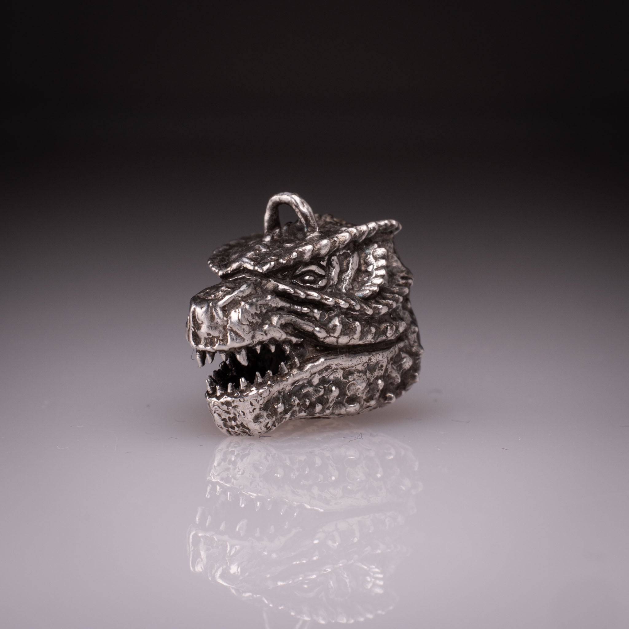 925 Sterling Silver Godzilla head pendant featuring detailed scales, sharp teeth, and oxidized finish, handcrafted by KaijuLab.