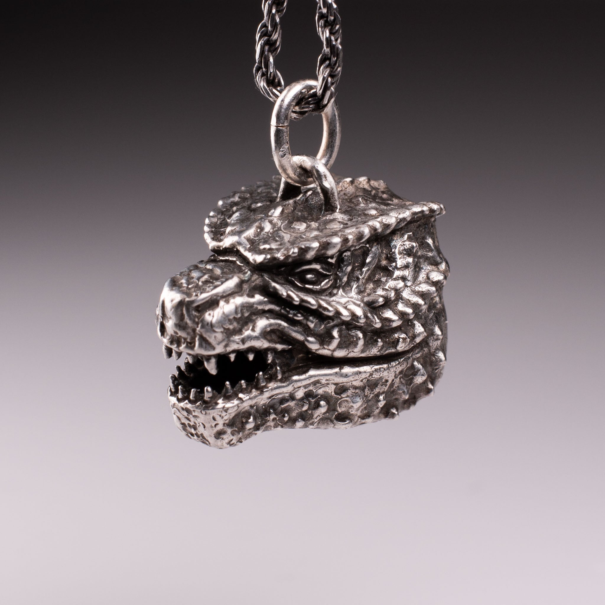 925 Sterling Silver Godzilla head pendant featuring detailed scales, sharp teeth, and oxidized finish, handcrafted by KaijuLab.