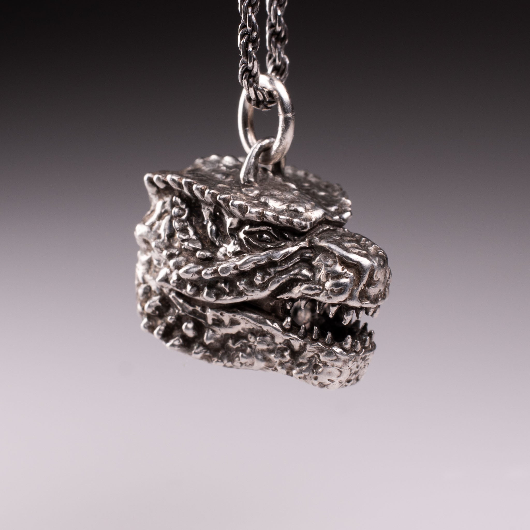 925 Sterling Silver Godzilla head pendant featuring detailed scales, sharp teeth, and oxidized finish, handcrafted by KaijuLab.